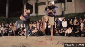 two people are dancing in front of a crowd on makeagif.com .