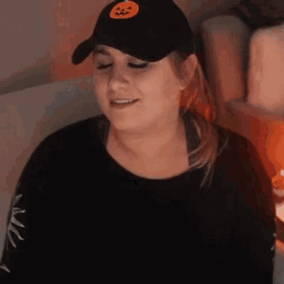 a woman wearing a black hat with a pumpkin on it is sitting on a bed .