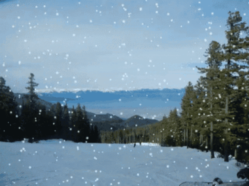 a snowy landscape with mountains in the background and snow falling