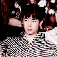 a man wearing a black and white striped shirt with a floral shirt behind him