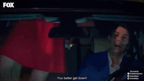 a woman in a red dress is sitting in the back of a car with the fox logo on the bottom right