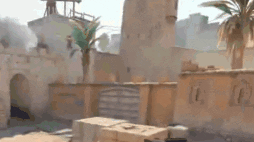 a blurred image of a desert landscape with palm trees and a building in the background .