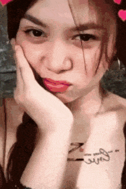 a young woman with a tattoo on her chest is making a funny face .