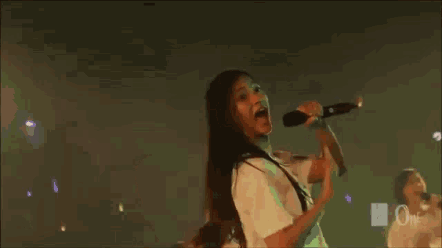a girl is singing into a microphone on a stage while dancing .