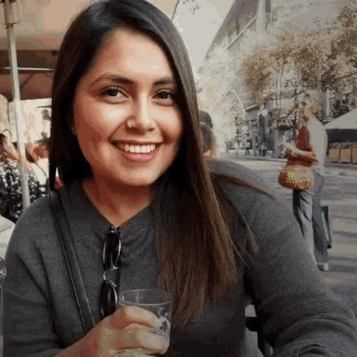 a woman is smiling while holding a glass