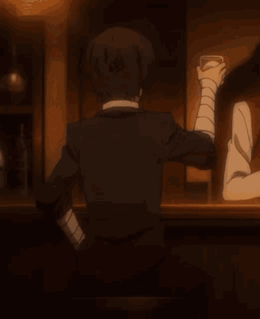 a man in a suit and tie is sitting at a bar holding a drink