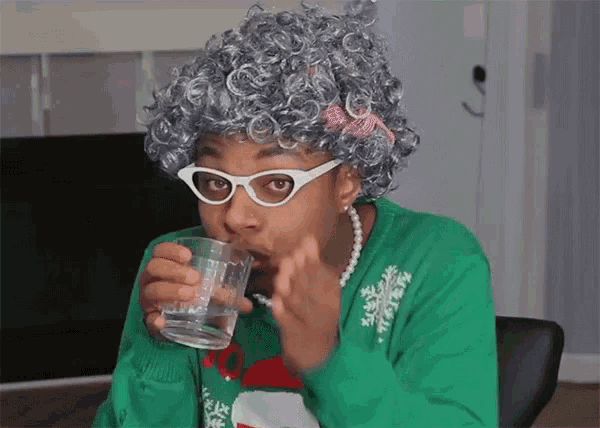 a woman wearing a wig and glasses drinks from a glass