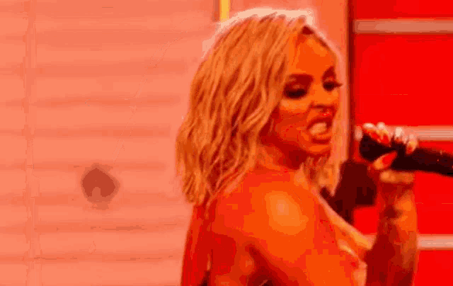 a woman is singing into a microphone in front of a red background .