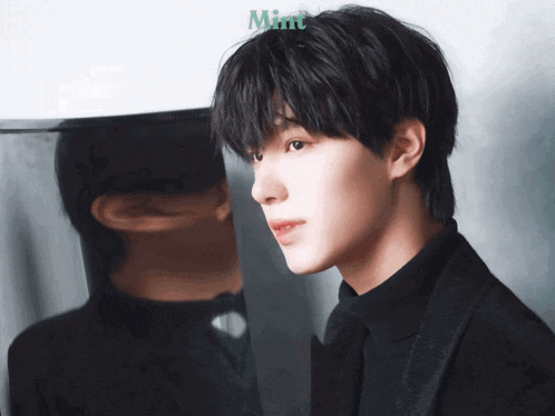 a man in a black suit is standing in front of a mirror with the word mint on the bottom right