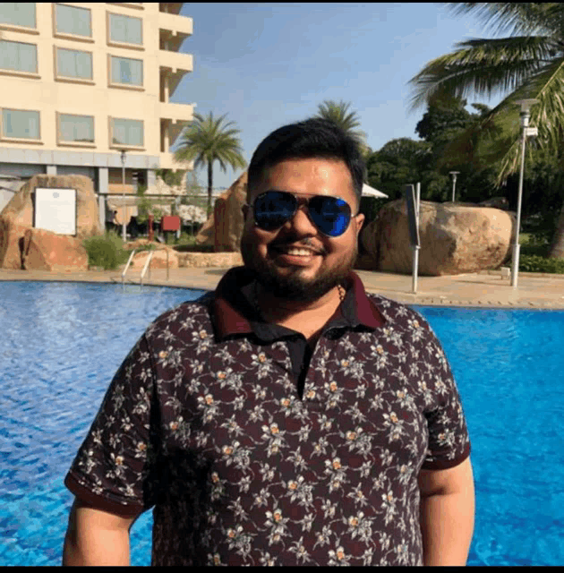 a man wearing sunglasses is standing in front of a pool