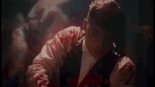 a man in a suit with blood on his sleeves is dancing .