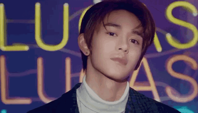 a young man is standing in front of a neon sign that says lucas .