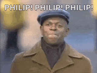 a man wearing a hat and a trench coat is making a funny face .