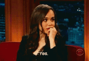 a woman is sitting on a red couch with her hand on her chin and says yes