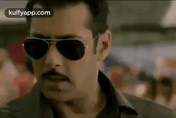 a man with a mustache is wearing sunglasses and a black shirt .