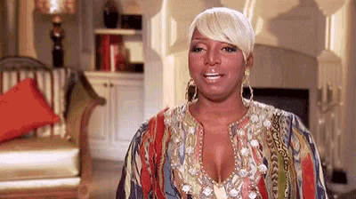 a woman wearing a colorful dress and earrings is standing in a living room .