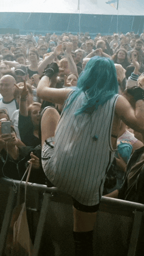 a woman with blue hair is dancing in front of a crowd