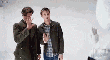 two men are standing next to each other and one of them is covering his face .