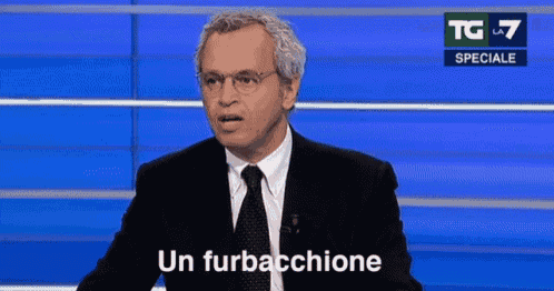 a man in a suit and tie is standing in front of a blue wall and saying un furbacchione .