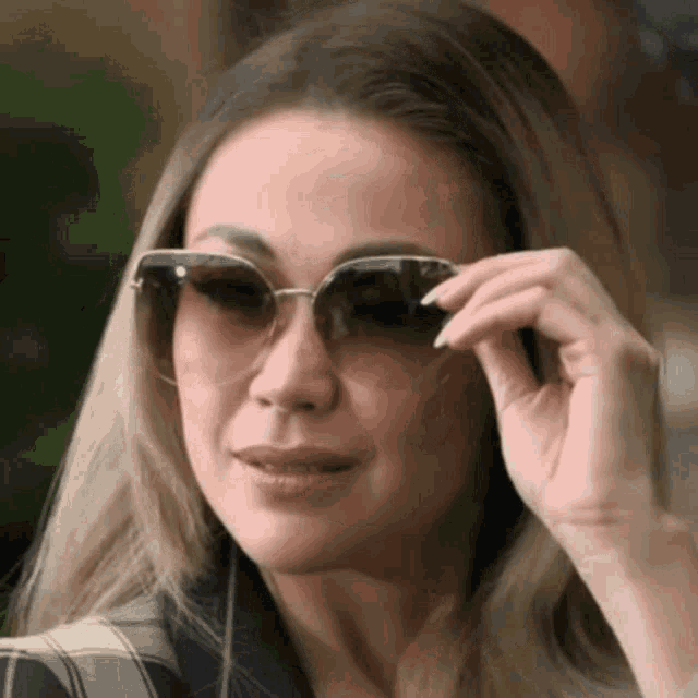 a close up of a woman wearing sunglasses and a plaid shirt