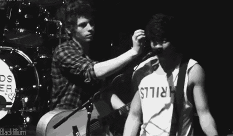 a man in a shirt that says thrills is standing next to another man on stage