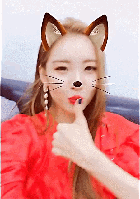 a woman with cat ears on her face is giving a thumbs up