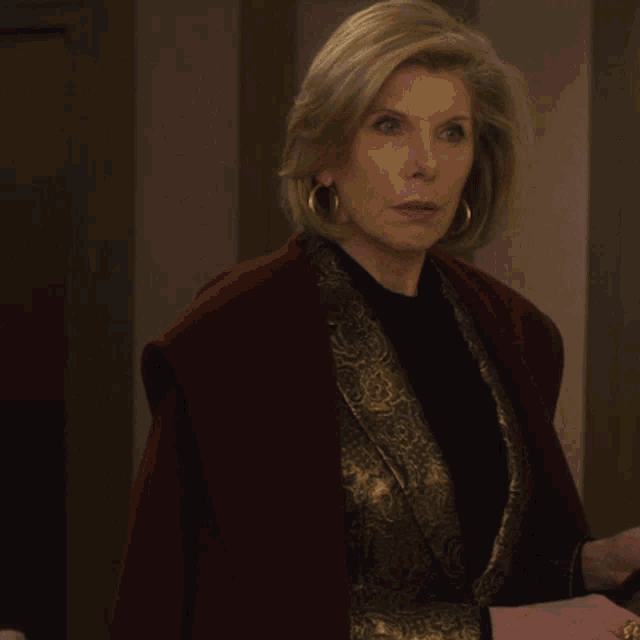 a woman wearing gold hoop earrings and a red jacket