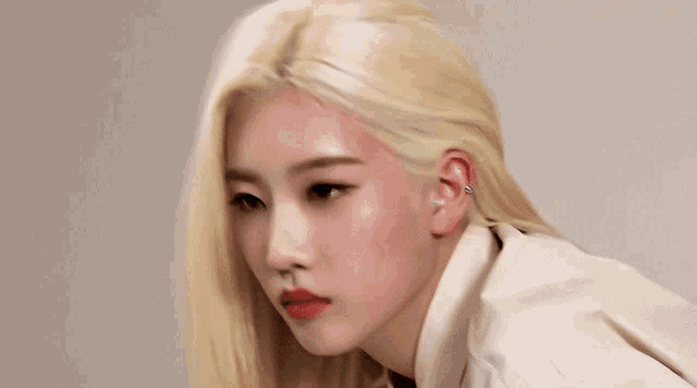a close up of a woman with blonde hair and red lipstick looking at the camera .