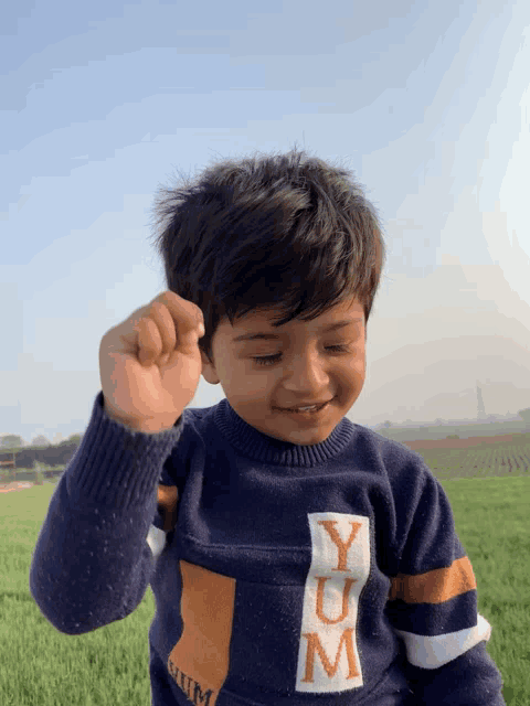 a young boy wearing a sweater that says yum on the front