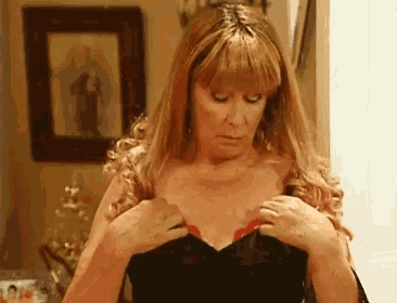 a woman is adjusting her bra in front of a picture of a man .
