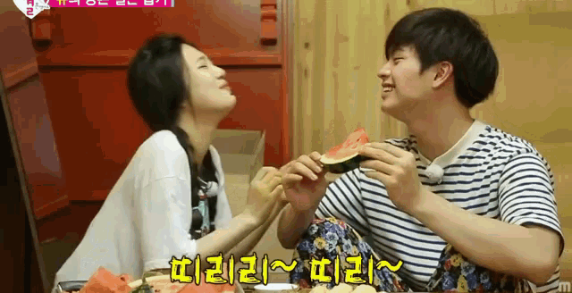 a woman is feeding a man a slice of watermelon with chinese writing on the bottom