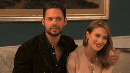 a man and woman are sitting on a couch and smiling