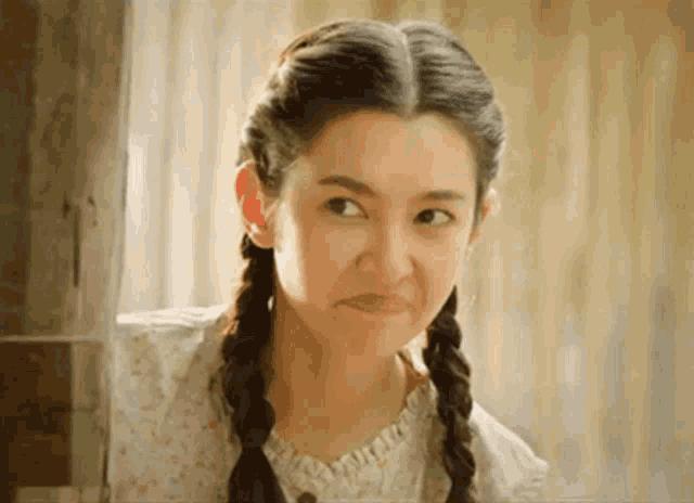 a young woman with braids is making a funny face .