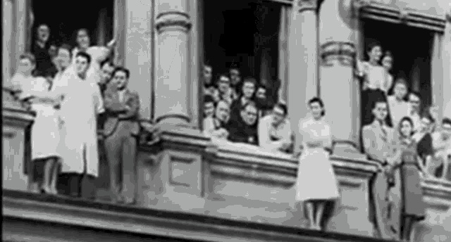 a black and white photo of a group of people standing outside of a building
