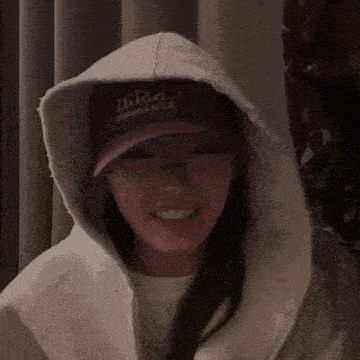 a woman wearing a hooded jacket and a hat that says 16124