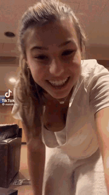a woman in a white shirt is smiling and making a funny face .
