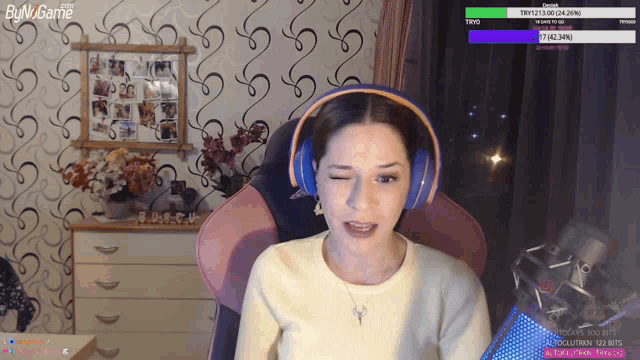 a woman wearing headphones sits in front of a screen that says byn game