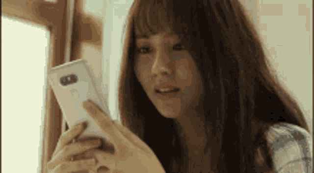 a woman is looking at her cell phone .