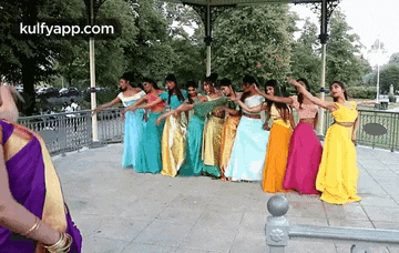 a group of women in colorful dresses are dancing on a stage .