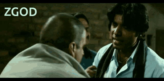 a man with a scarf around his neck is talking to another man with the word zgod on the bottom