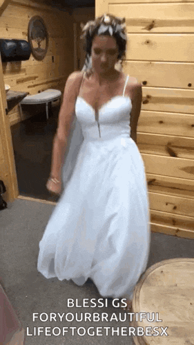 a woman in a white wedding dress is dancing in a room with a wooden wall .