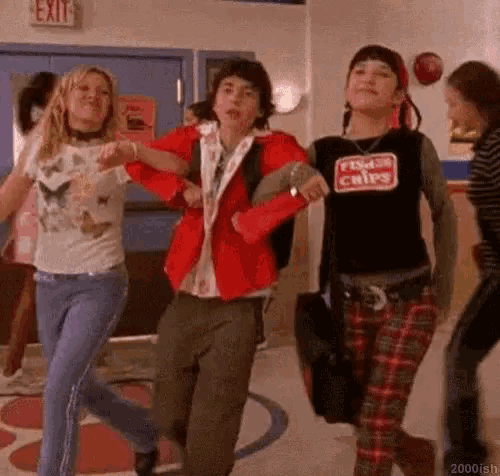 a group of young people are dancing in a hallway in a school .
