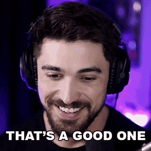 a man with a beard wearing headphones is smiling and says that 's a good one