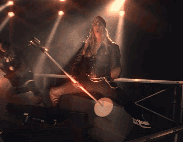 a woman singing into a microphone while a man plays a guitar