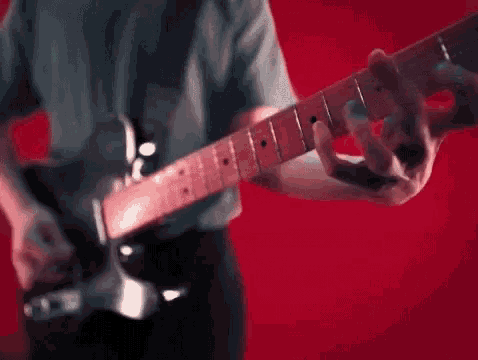 a man is playing an electric guitar on a red background .
