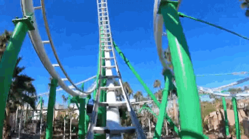 a roller coaster with green poles and a blue sky in the background .