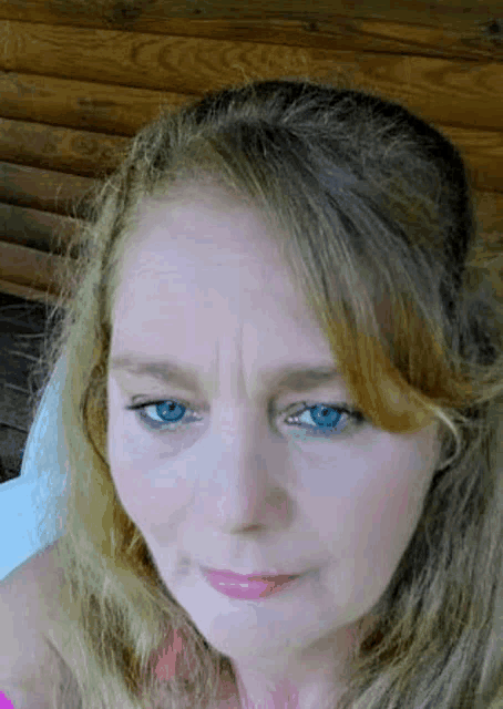 a close up of a woman 's face with blue eyes and blonde hair looking at the camera .