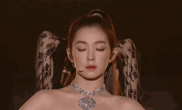 a close up of a woman wearing a necklace and a ponytail .