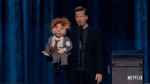a man in a suit is holding a puppet in front of a netflix sign