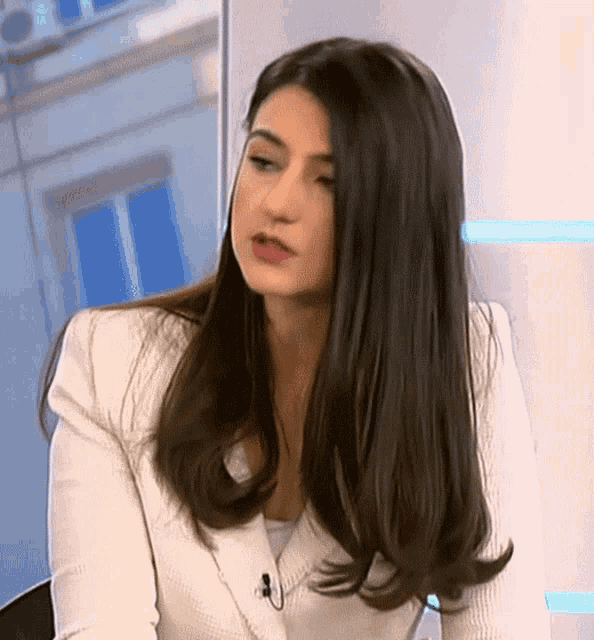 a woman with long dark hair is wearing a white jacket and a white shirt